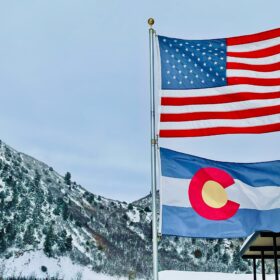 American flag and Colorado state flag flying together at a Colorado mountain community property