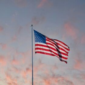 Tall commercial flagpole flying a large American flag against a Colorado sky