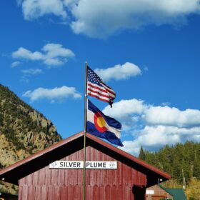 Statehood anniversary flags — American and Colorado state flags flying together in a Colorado mountain town