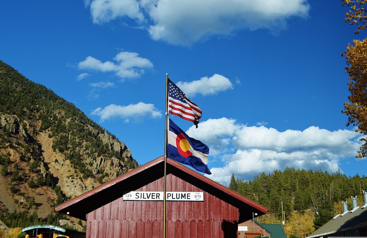 Statehood anniversary flags — American and Colorado state flags flying together in a Colorado mountain town