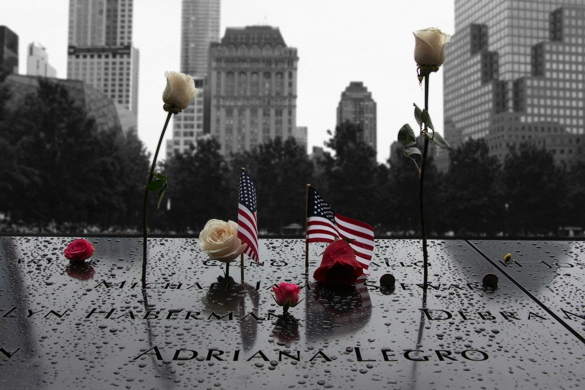American flags and white roses placed on the engraved names at the National September 11 Memorial in remembrance