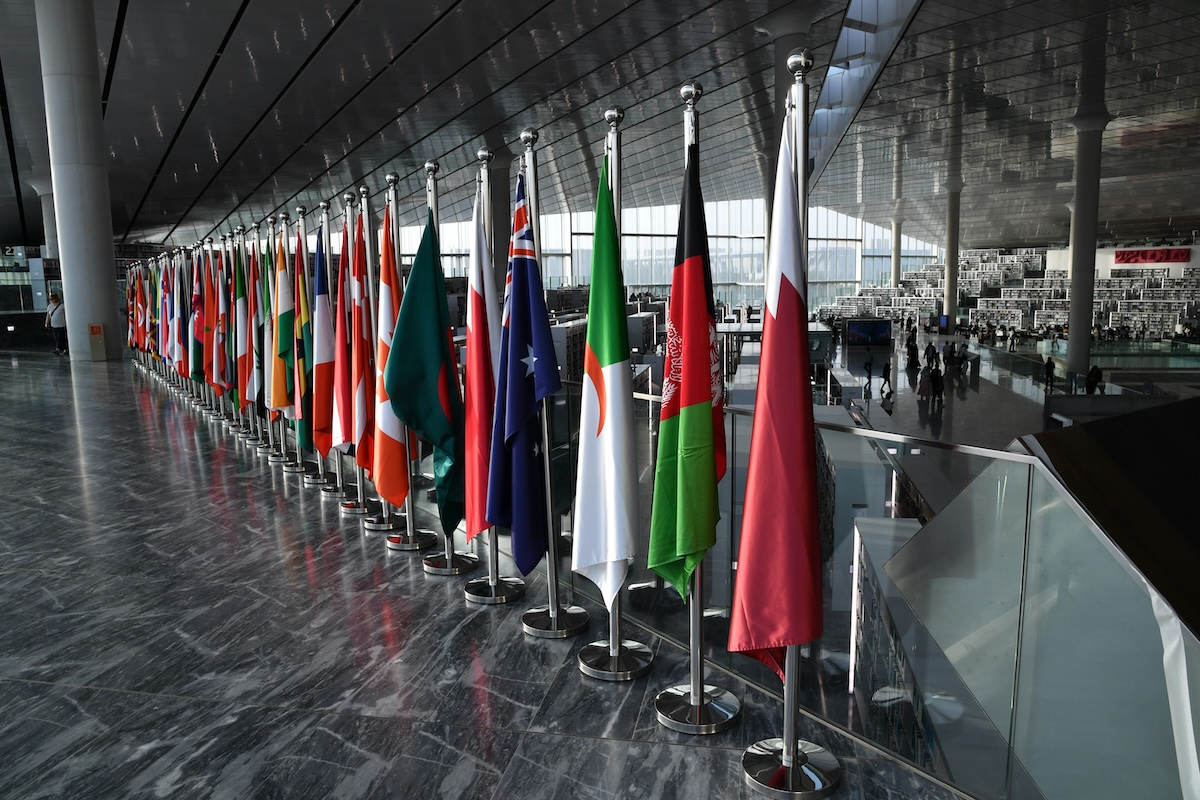 Row of international country flags on indoor floor stands at a public building